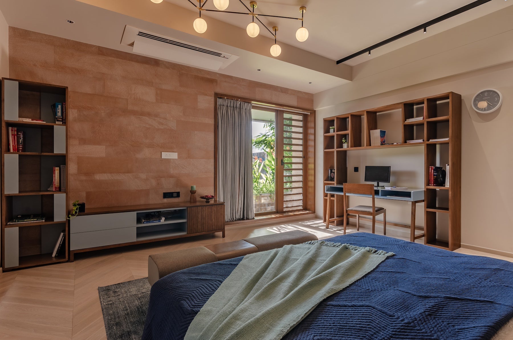 modern master bedroom with custom wooden furniture. The wooden study table, and bookshelf with matching entertainment console makes the room perfect for rewind. Along with that you also have an upholstered bench for extra seating