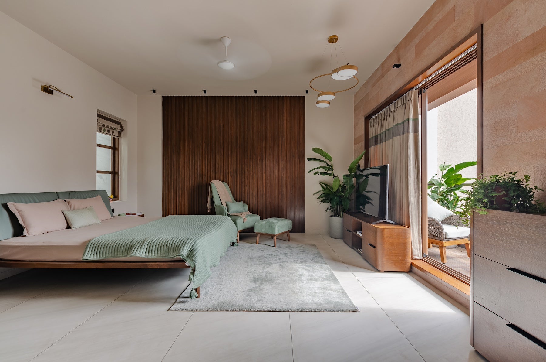 modern master bedroom with wooden furniture. Custom king size bed with a contrast of mint green, accent chair with matching foot rest and Wooden TV unit with hidden drawers and storage. Keeping it modern yet vintage